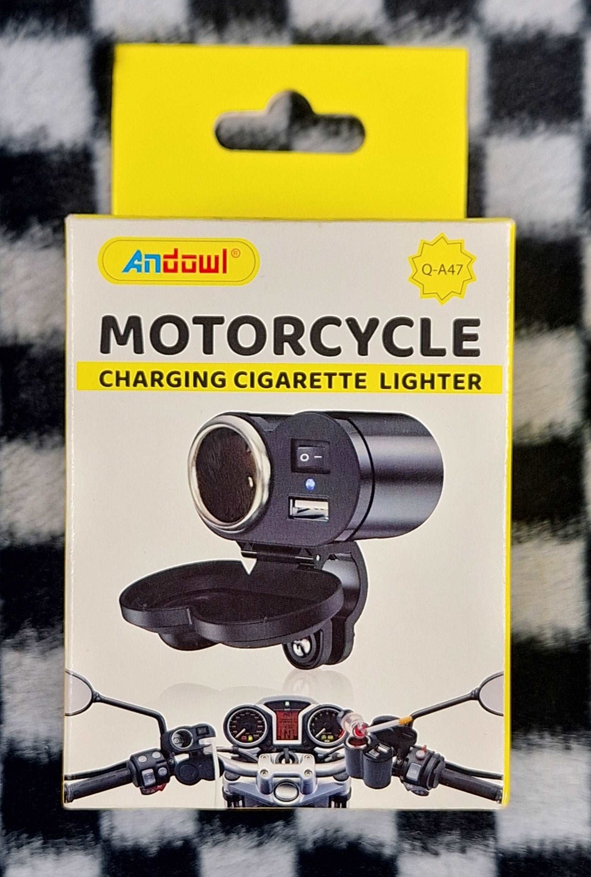 Motorcycle charging lighter socket by Little Tokyo SA, close-up view of black electrical accessory for motorcycle power outlets.